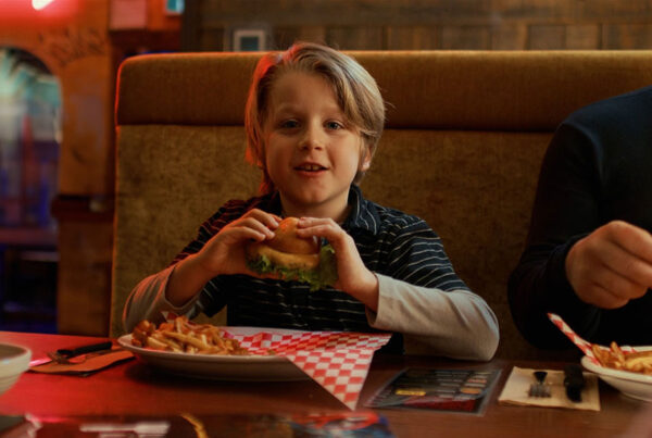 Jeune garçon qui mange un hamburger chez La Belle et La boeuf